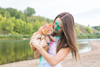 Woman carrying cat while standing outdoors