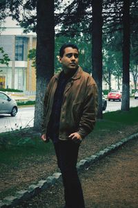 Young man standing by tree trunk