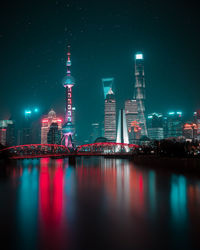 Oriental pearl tower by huangpu river in city at night