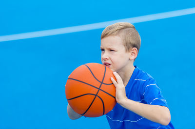 Boy aiming basketball while standing on sports court