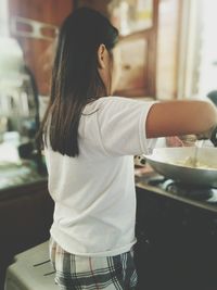 Rear view of woman cooking in kitchen at home