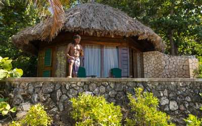 Tropical thatched roof beach house on rocky cliff with palm trees in the caribbean