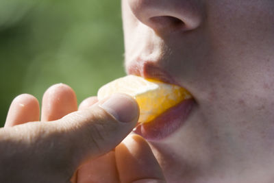 Cropped image of person eating orange