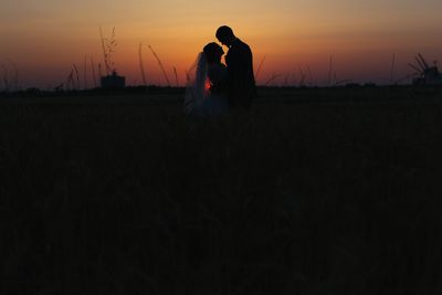 Silhouette people standing on field against sky during sunset