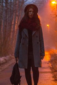 Portrait of young woman standing on road at night