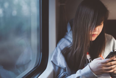 Woman using smart phone while sitting in train