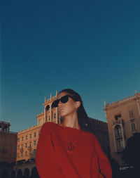 Young woman standing against clear blue sky