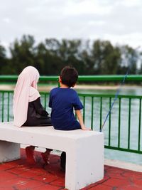 Rear view of people sitting on bench
