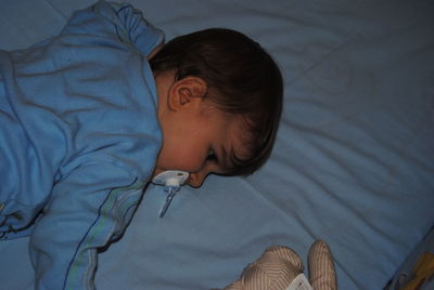 Cute baby boy sucking pacifier in crib at home