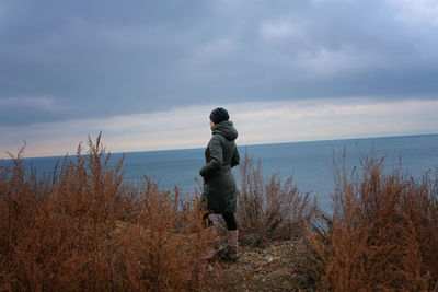 Rear view of man looking at sea against sky