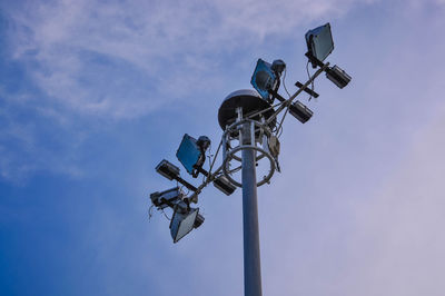 Low angle view of floodlights against blue sky