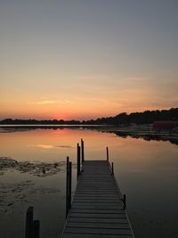 Pier over lake against sky during sunset