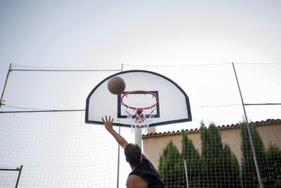 Low angle view of man playing basketball against clear sky