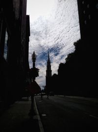 Road by silhouette city against sky