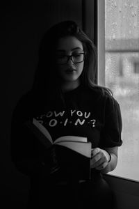 Portrait of a young woman standing against wall