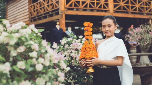 Full length of a beautiful young woman standing by flowering plants