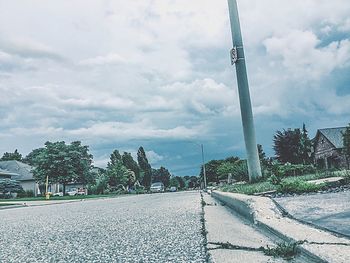 Road by trees against sky