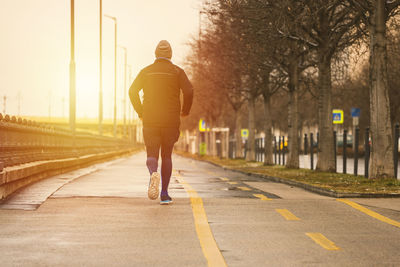 Rear view of man cycling on street in city