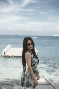 Portrait of young woman wearing sunglasses against sea