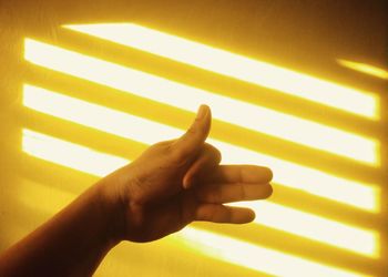 Close-up of human hand on illuminated wall