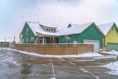 Snow covered houses by building against sky