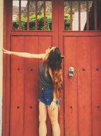 Young woman standing against door