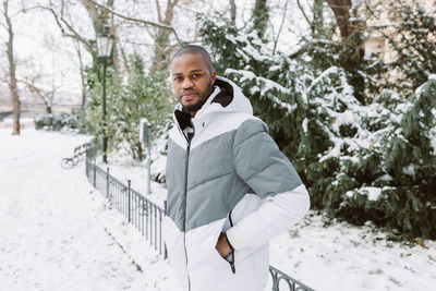 Young african man in park, snow winter season, city portrait