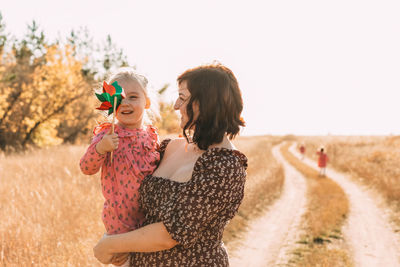 Mom shows little daughter how to use a windmill on outdoor. esg and clean energy concept.