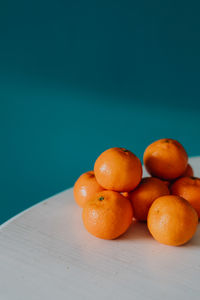 Close-up of orange fruits on table against blue background