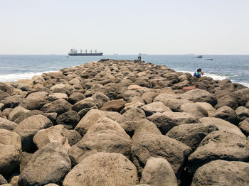 People on beach by sea against clear sky