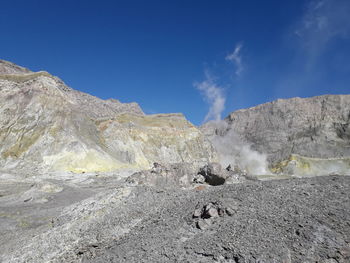 Scenic view of volcanic mountain against blue sky