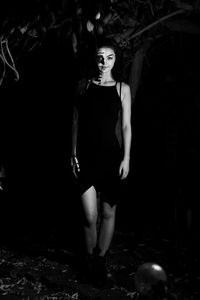 Portrait of young woman standing against black background