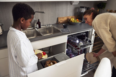 Mother and son loading dishwasher