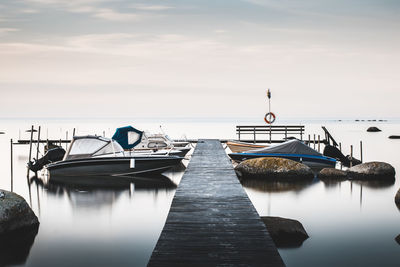 Boats moored at harbor against sky
