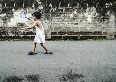 Full length of boy walking on street against wall