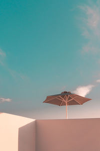 Low angle view of umbrella on building against blue sky