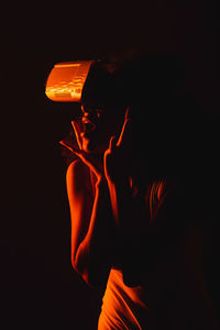 Woman holding illuminated light against black background