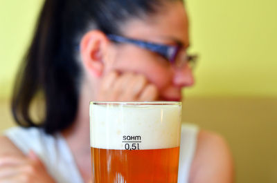 Close-up of beer glass with woman in background