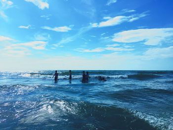 People swimming in sea against blue sky