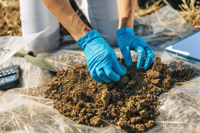 Low section of agronomist analyzing soil on field