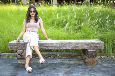 Full length portrait of young woman sitting outdoors