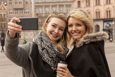 Portrait of smiling young woman using phone in city