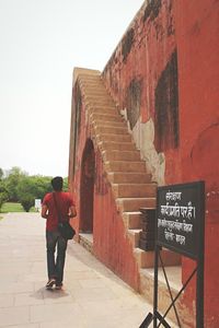 Rear view of man walking on road against clear sky