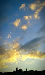 Low angle view of silhouette trees against cloudy sky