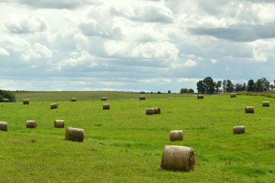 Hay bales on field against sky