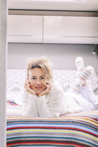 Portrait of smiling young woman standing against wall