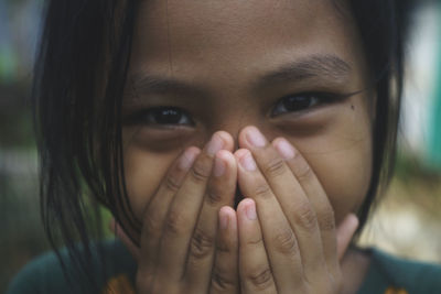 A child is covering his mouth smiling