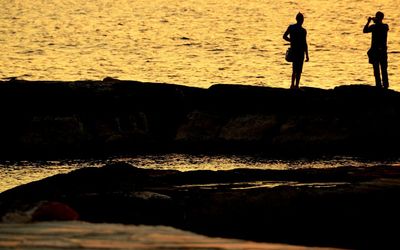 Silhouette of people on beach at sunset