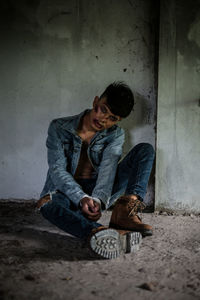 Portrait of wounded man sitting against wall