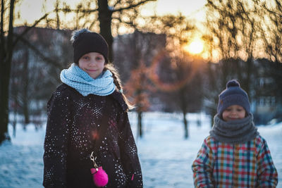 Portrait of smiling sibling standing in snow